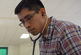 In the photo on this page, Dr. Gene F. Kwan, wearing a checkered shirt, attends to a patient lying in a hospital bed in Haiti 