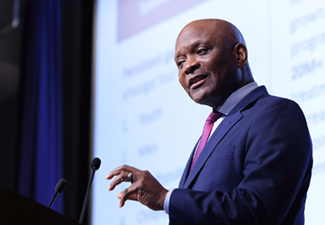 Ambassador Dr. John Nkengasong stands at a podium with a slide projected on a large screen behind him during the David E. Barmes Global Health Lecture 2024 at the U.S. National Institutes of Health on June 6, 2024.